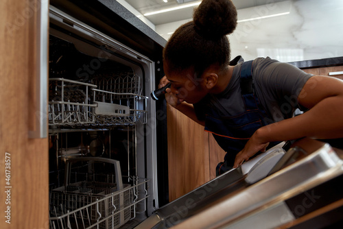 Young service woman looking inisde dishwashing machine photo