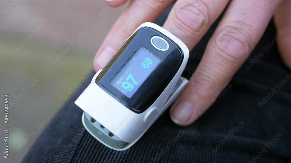 Women's hands measure oxygen levels using a pulse oximeter. A pulse