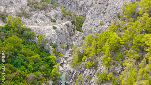 Flight among the rocky mountains above the hiking trail in a deep prehistoric gorge among the green coniferous forest. High quality 4k footage