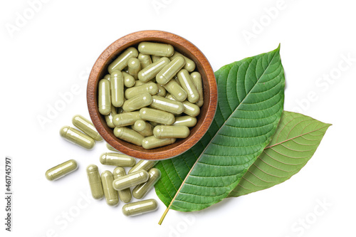 Flat lay of Kratom (Mitragyna speciosa) capsules with fresh leaves isolated on white background. photo