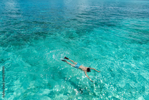 Man snorkeling in clear tropical waters in front of exotic island