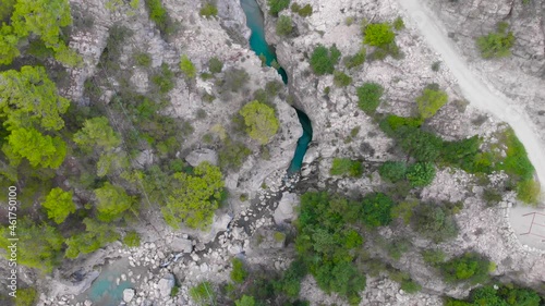 Fly over a small mountain river and a hiking trail in a deep prehistoric gorge in the middle of a green coniferous forest. High quality 4k footage