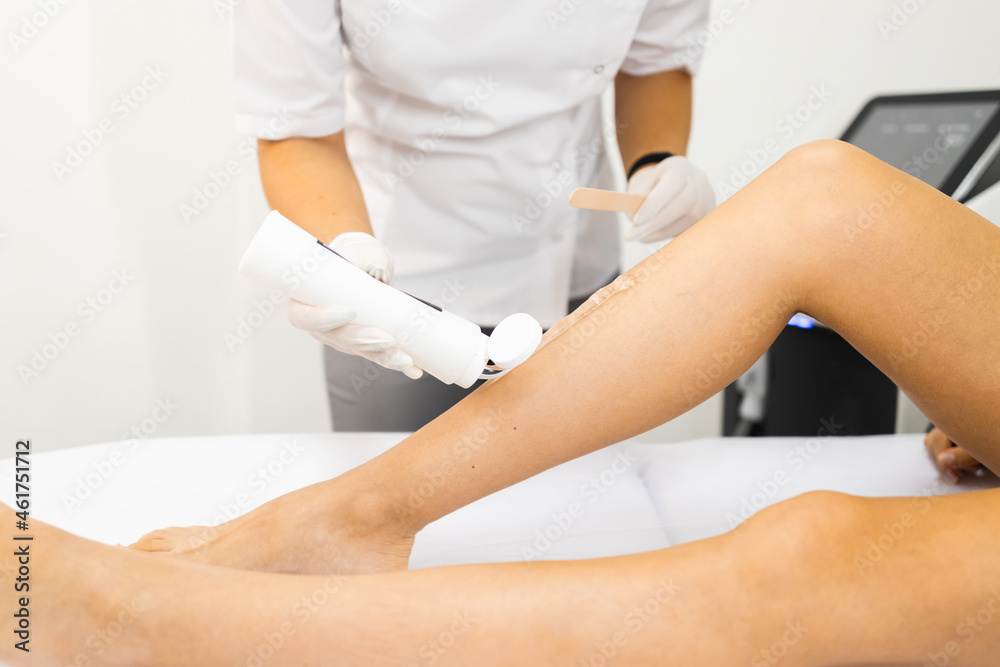 Fototapeta premium Beautician applies a special gel for laser hair removal to a woman's leg