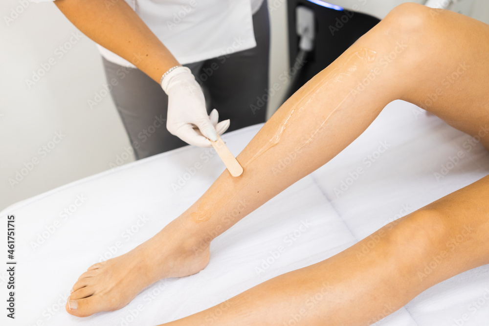 Beautician applies a special gel for laser hair removal to a woman's leg