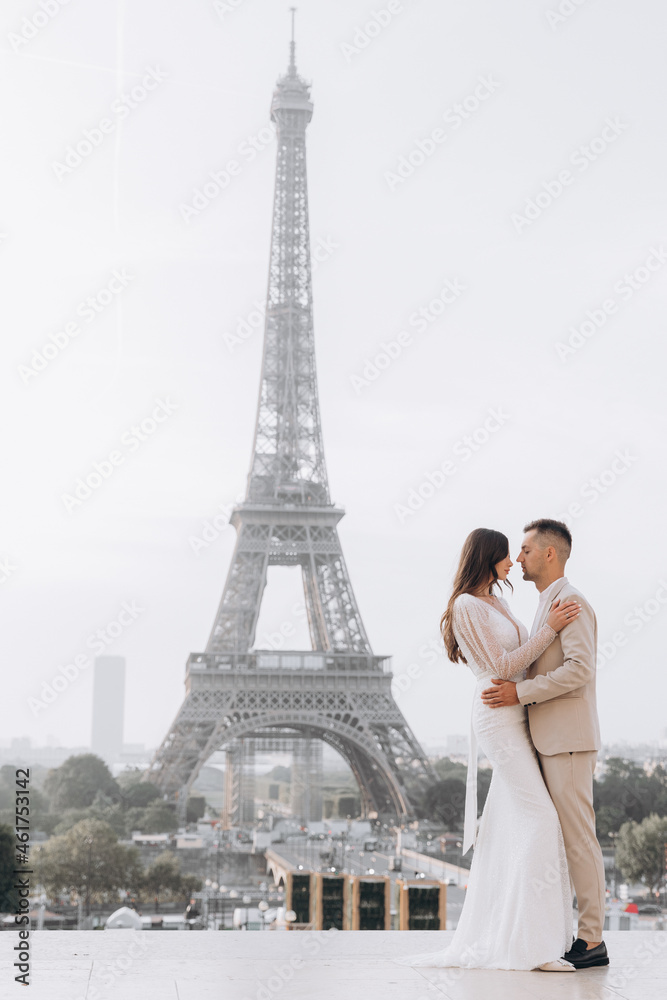 Wedding couple kissing in front of the Eiffel tower in Paris, France. A man kisses his woman.