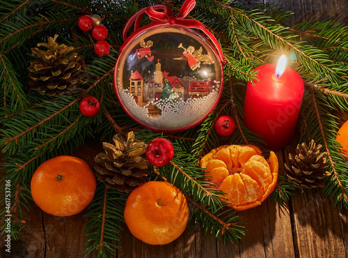 Christmas New Year composition with tangerines. red burning pine cone candle on a dark wooden background. 