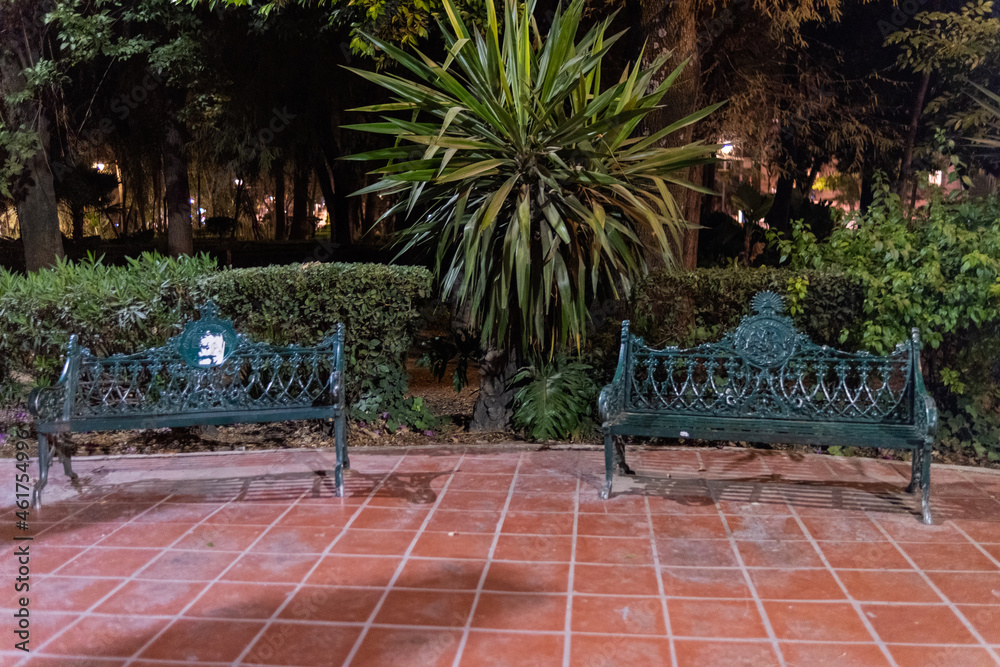 Obraz premium Green metal benches on tiled floor from park at night