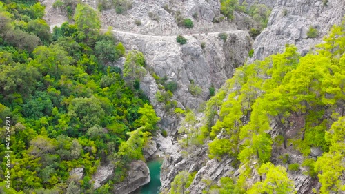 Flight among the rocky mountains above the hiking trail in a deep prehistoric gorge among the green coniferous forest. High quality 4k footage