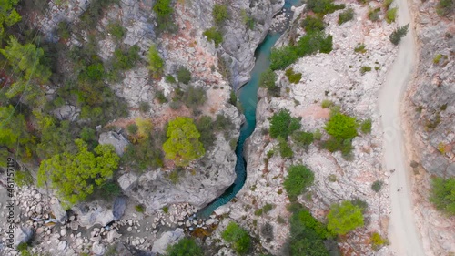 Flight among the rocky mountains above the hiking trail in a deep prehistoric gorge among the green coniferous forest. High quality 4k footage
