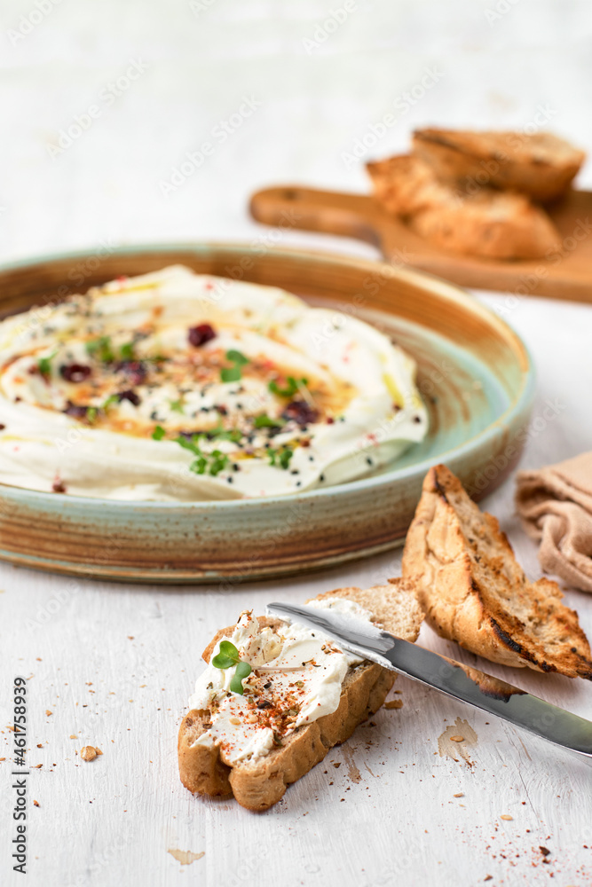 Feta with herbs, spicy honey and mini baguette on a plate on a rustic background. Vegetarian menu, healthy food.