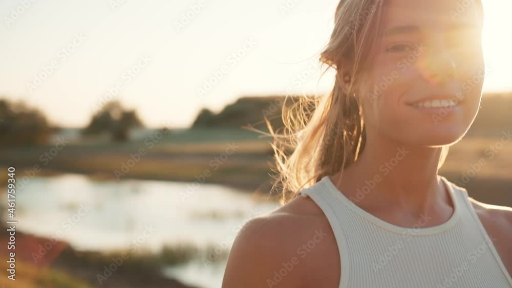 Close-up view of smiling tourist woman looking at the camera and walking near the lake