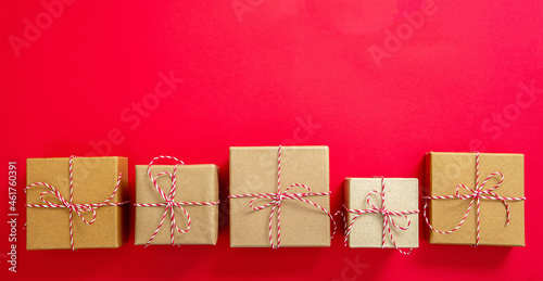 Christmas gift boxes on red color background. Red white striped string tied on brown kraft presents. photo