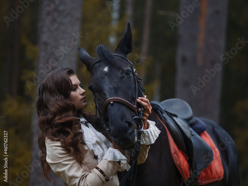 Portrait of a rider in a retro suit and her black horse.