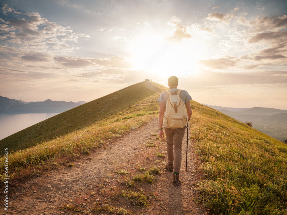 Young man travels alone walking on trail and enjoying on view of mountains and sea landscape at sunset , the lifestyle concept of traveling outdoors.