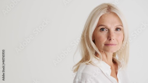 Side view of the concentrated mature woman looking at the camera in the white studio photo
