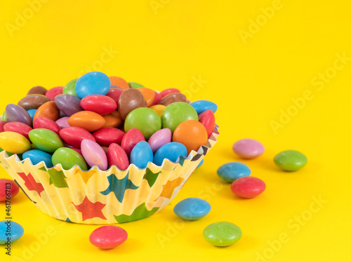 White plate on a yellow background full of multi-colored sweets