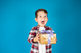 Cute boy holds present box and very surprised. Concept of holidays and birthday.
