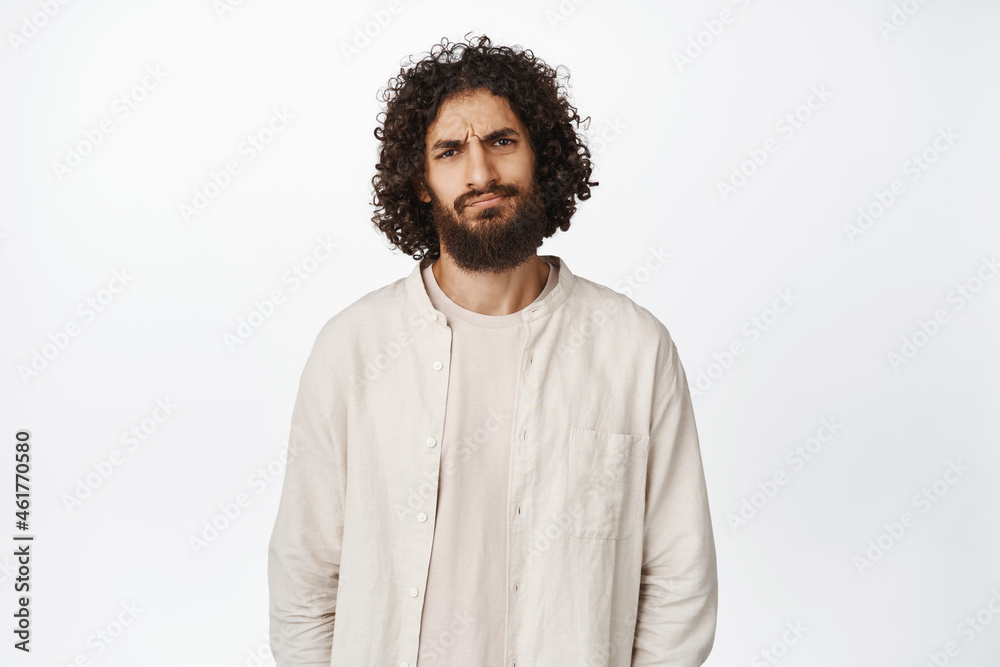 Portrait of man sulking and frowning, disapprove smth, dislike and express disappointment, white background Portrait of man sulking and frowning, disapprove smth, dislike and express disappointment, white background