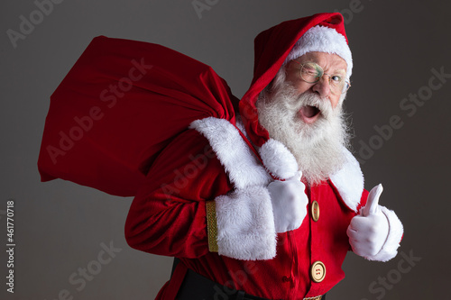 Santa Claus in eyeglasses is looking at camera and smiling, on gray background photo