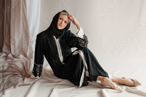 Beautiful muslim woman in traditional arabian abaya dress on gray background