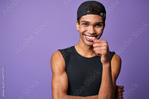 Portrait of smiling young brunette man in black t-shirt and cap. Happy latino model of trans gender photo