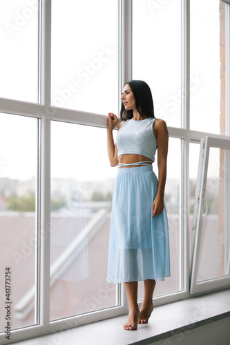Beautiful young woman looking with smile while standing at windowsill at home Free Download Beautiful young woman looking with smile while standing at windowsill at home - GFXLoad