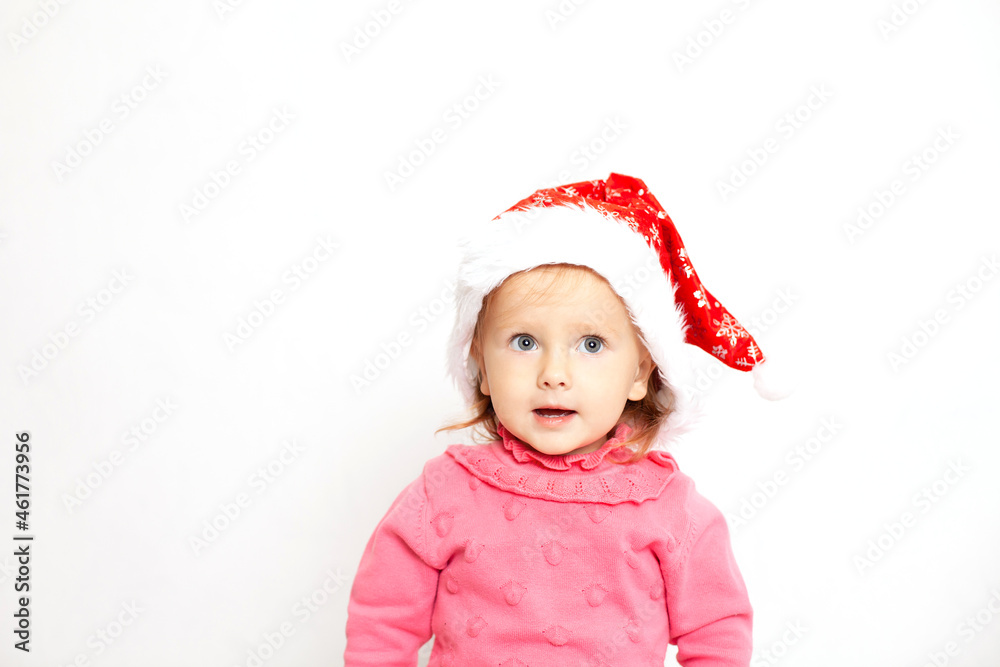 Portrait of a cute girl with blue eyes in a Christmas cap and a pink jumper. White background, space for text. New Year Portrait of a cute girl with blue eyes in a Christmas cap and a pink jumper. White background, space for text. New Year