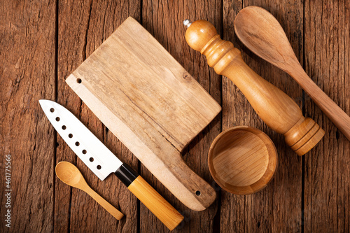 Cutting board with kitchen utensils on rustic background.