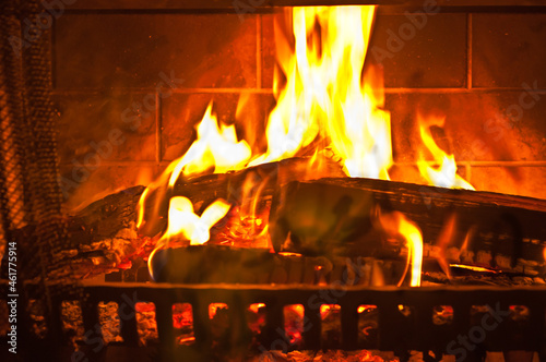 front view, close distance, of flames from a wood fire, contained by an iron grate, in a fireplace, of a cabin, on a rainy evening, in Georgia mountains