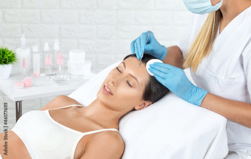 A procedure for cleansing the skin of the face from blackheads and acne. Cosmetologist treats problematic skin of a young woman's face in a beauty salon. Aesthetic cosmetology and makeup concept. A procedure for cleansing the skin of the face from blackheads and acne. Cosmetologist treats problematic skin of a young woman's face in a beauty salon. Aesthetic cosmetology and makeup concept.