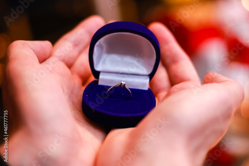 Gold ring, wedding ring in red box and, red heart on white-red background with beautiful bokeh. The moment of a wedding, anniversary, engagement, or Valentine's Day. Happy day.