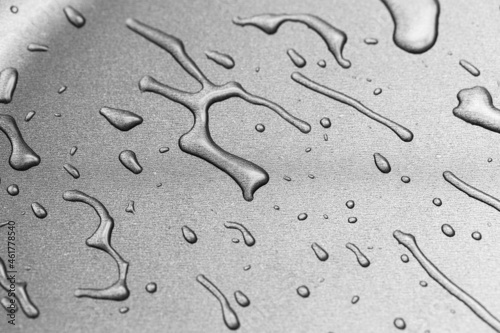 The surface of a frying pan with drops of transparent oil in close-up. Texture of metal cookware for frying