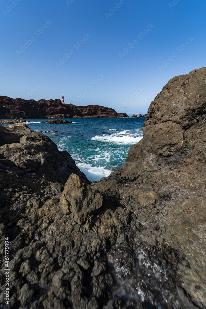 Rocky coast of the Atlantic Ocean at Cape Teno. A lighthouse in the background. Tenerife. Canary Islands. Spain.