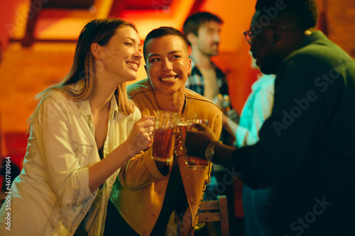 Young happy adults toast and celebrate their friendship during their night out in pub.