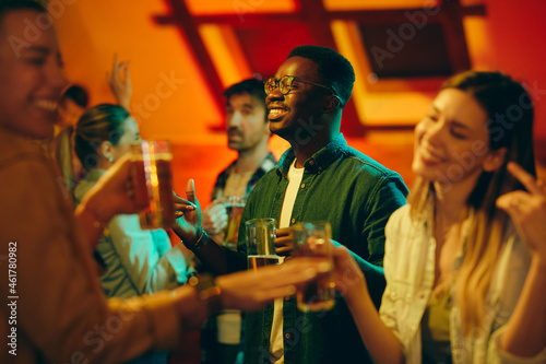 Young African American man has fun and dances on night party in bar.
