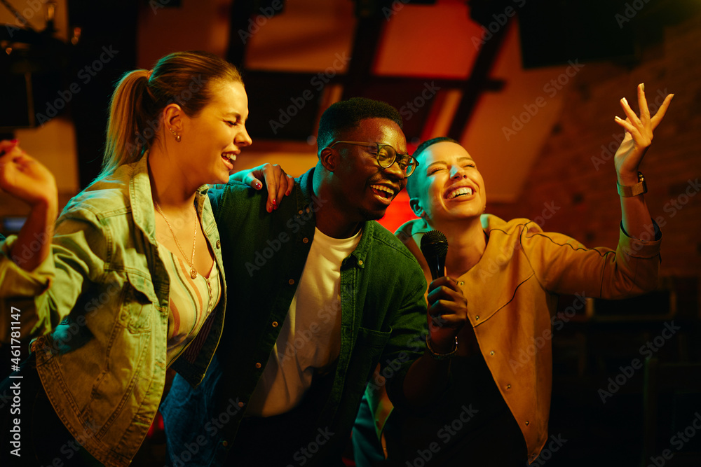African American man and his female friends sing karaoke and have fun during their night out in bar.