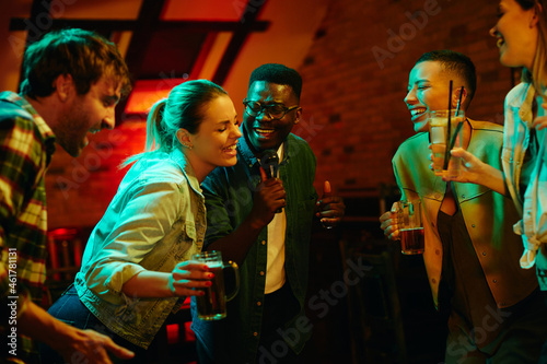 Multi-ethnic group of young people have fun during karaoke party in bar.