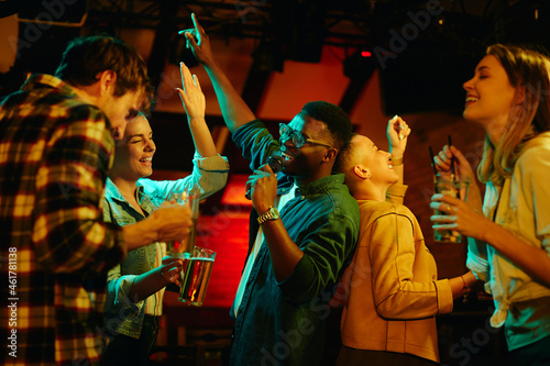 Happy black man sings while being on karaoke party with his friends in pub. photo