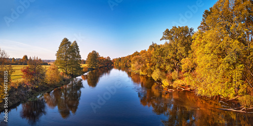Fall colorful trees reflecting in water, picturesque background. Wild forest, river, meadow sunset panorama