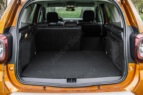 Huge, clean and empty car trunk of a modern compact suv. Rear view of a SUV car with open trunk and one folded seat. Car trunk interior. © Roman