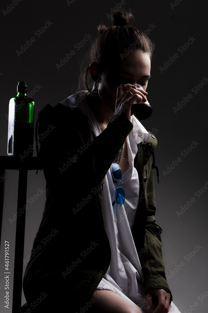 studio portrait of a beautiful girl with alcohol bottle and a plastic cup studio portrait of a beautiful girl with alcohol bottle and a plastic cup