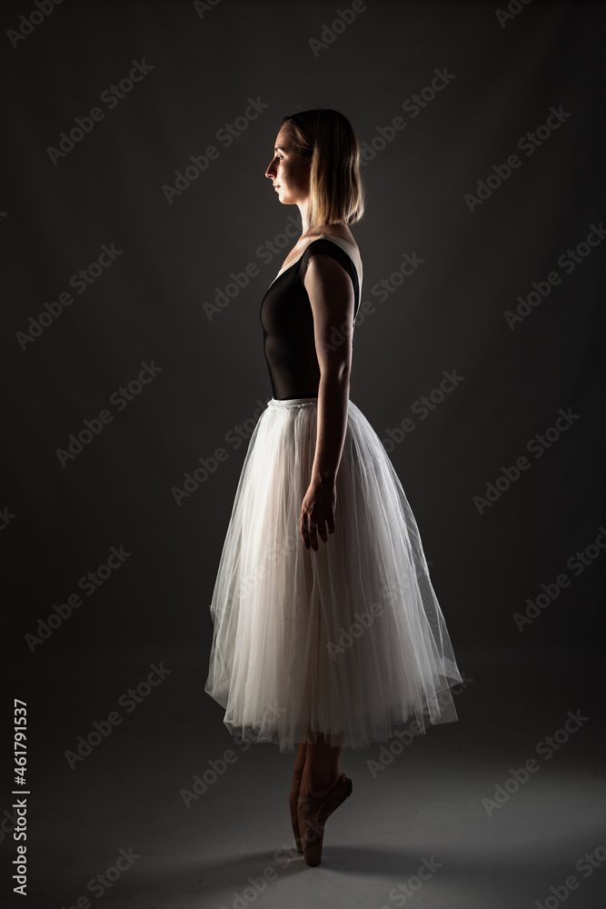 ballerina with a white dress and black top posing on gray background. ballerina with a white dress and black top posing on gray background.