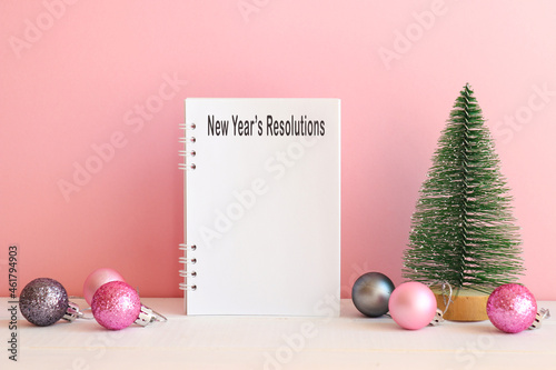 New Year Resolutions list. Festive background with Christmas tree toy, Christmas balls, and notebook for writing goals or results of the year. Holiday and motivation concept