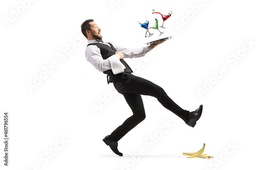 Full length shot of a waiter slipping on a banana peel and falling with a tray of coctails photo