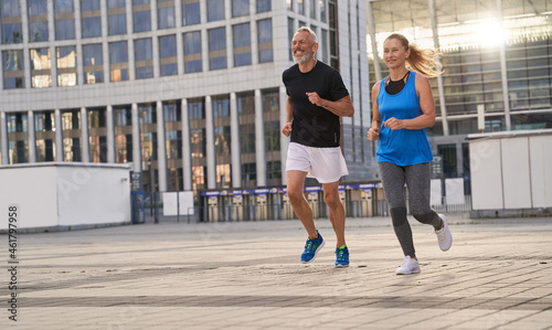 Mature couple, man and woman exercising and jogging together in the city on a warm summer day