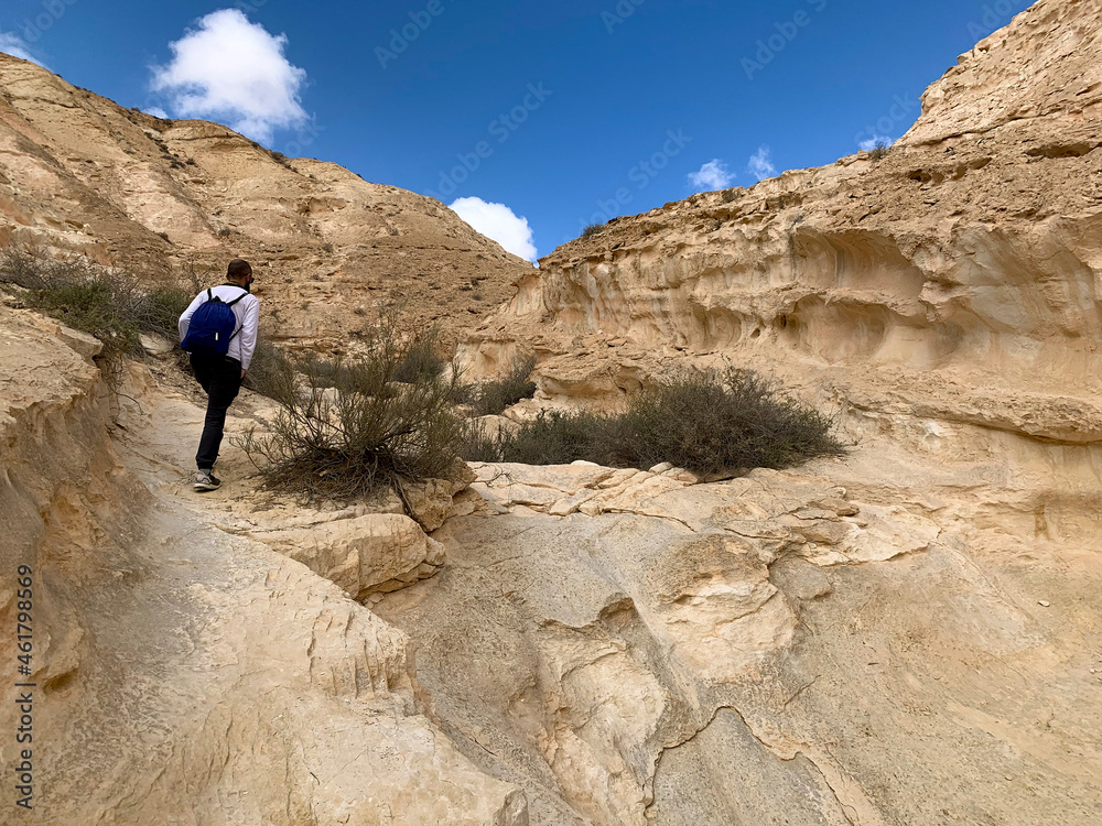 Tourist walks along hiking trail through Wadi Hawarim - a dry bed among the mountains in the Negev desert