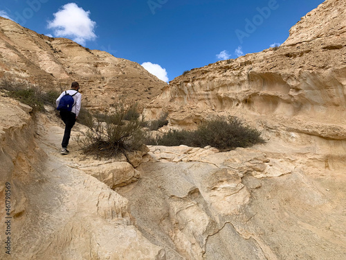 Tourist walks along hiking trail through Wadi Hawarim - a dry bed among the mountains in the Negev desert