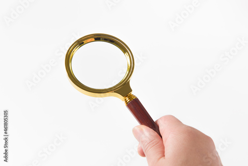 hand holding brass magnifying glass isolated on white background