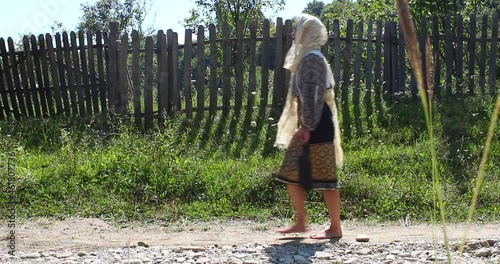 Girl walking barefoot on a dirt road dressed in Traditional Costume from Arges Region. photo