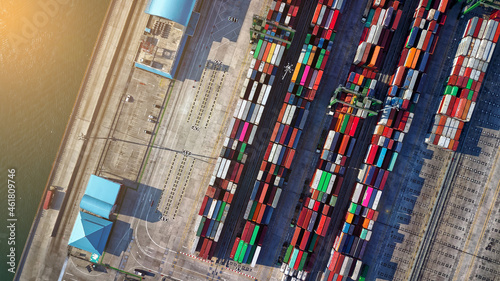 Logistics and transportation of Container Cargo ship and Cargo plane with working crane bridge in shipyard at sunrise, logistic import export and transport industry background
